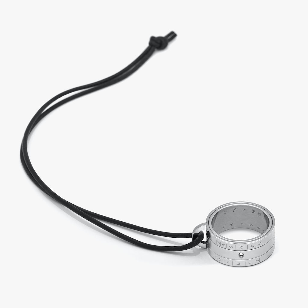 Sundial ring from stainless steel, with laser-cut time and month markers. 19 mm diameter. Goat leather cord, black.